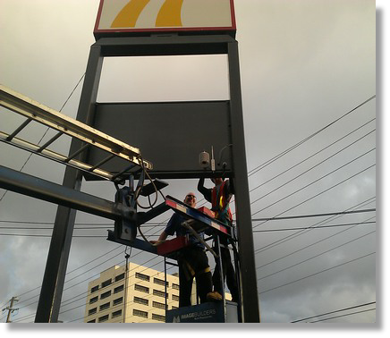 Photo of sign being serviced from a bucket truck.